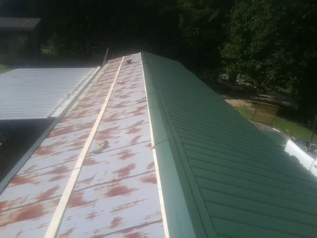 Old rusted panels beside newly installed green metal roofing — Wind Damage Roof Repair by Roofing Brothers in Sea Girt