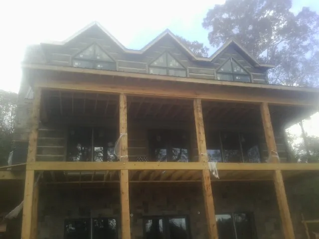 Dormers and porch framing on a large log home under construction — Roof Coating work by our crew in Sea Girt