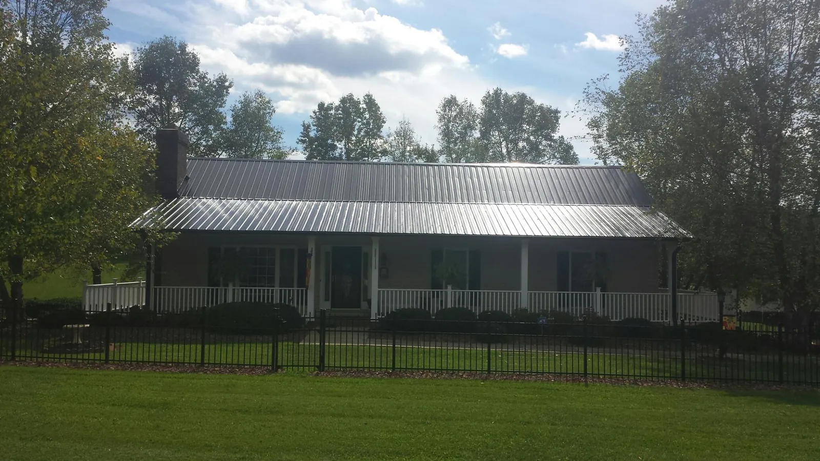 Gray metal roof on a brick ranch with a full width front porch — Gutter Guard Installation work by our crew in Sea Girt
