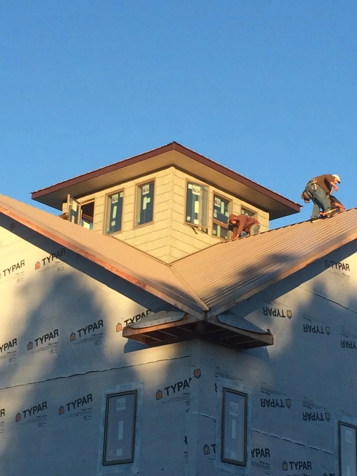 Roofers working around a rooftop cupola on a new metal roof at sunset — Roof Waterproofing in Sea Girt by Roofing Brothers